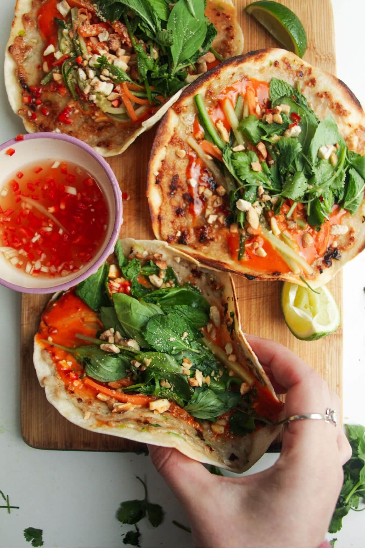 Three chicken banh mi tacos on a wooden board.